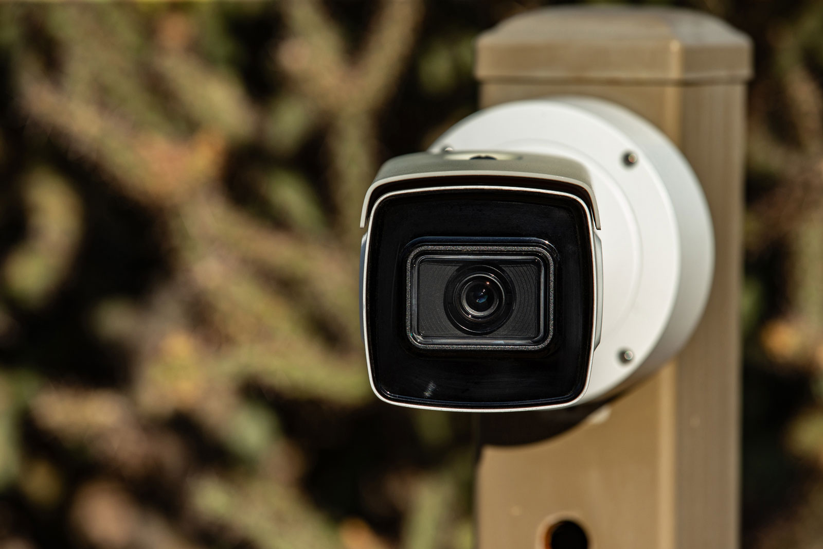 ParkPro maintenance technician cleaning and adjusting outdoor security camera at Phoenix property