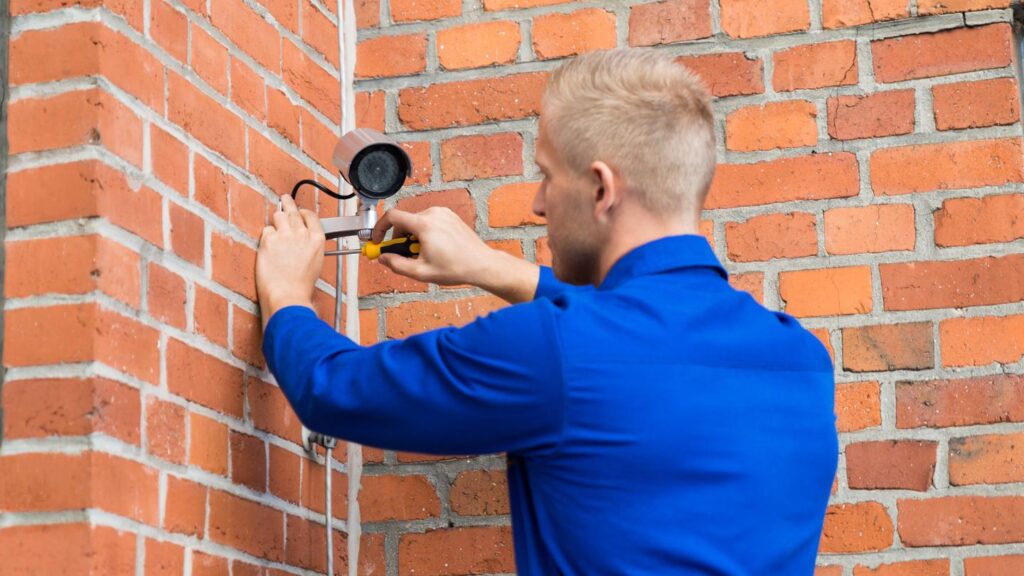 ParkPro technician repairing malfunctioning security camera at commercial building in Phoenix AZ